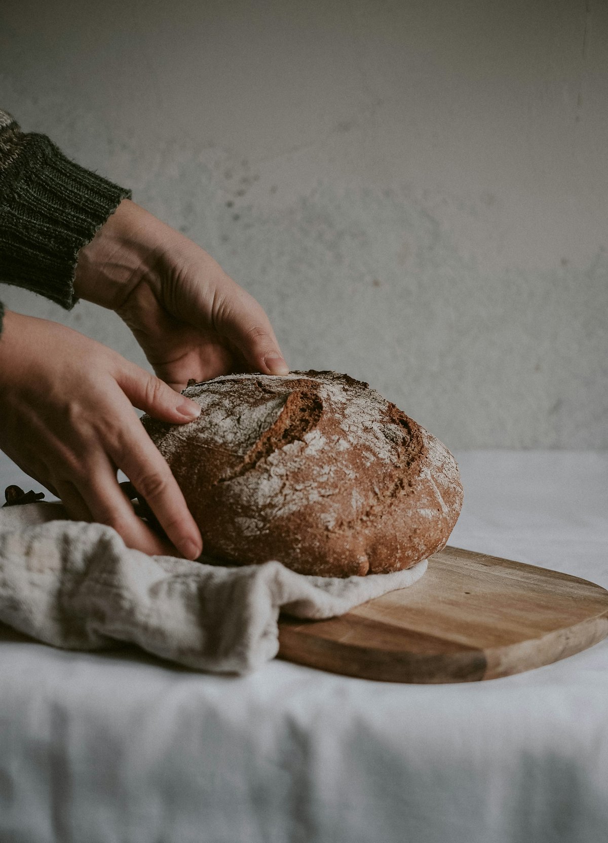 Hands holding a fresh sourdough loaf